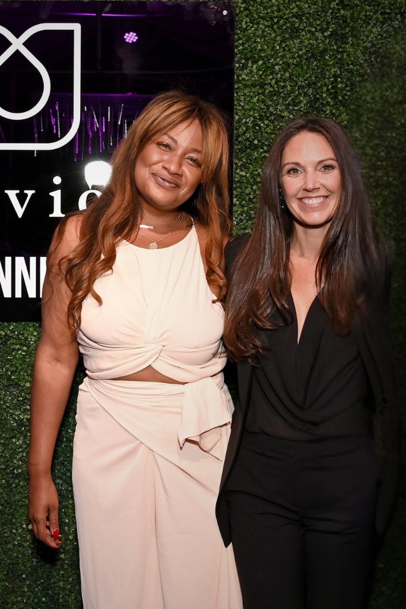 Two women stand smiling at the camera.