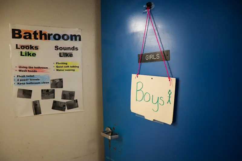 A manilla folder that says “boys” hangs on a blue door, where a permanent sign says “girls.”