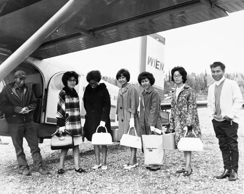 Six students and a pilot stand next to a small plane.