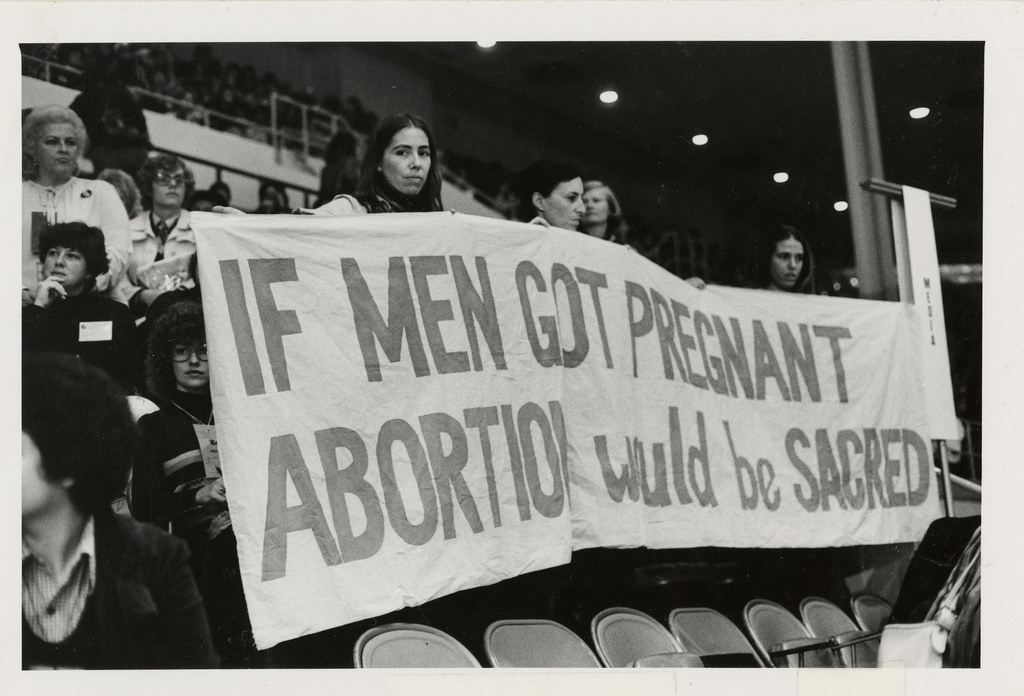 Photograph of Women Holding Banner, “If Men Got Pregnant Abortion Would be Sacred” at the National Women’s Conference, 1977