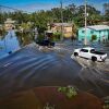 A car drives through a flooded neighborhood