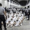 In this photo provided by El Salvador's presidential press office, a prison guard transfers deportees from the U.S., alleged to be Venezuelan gang members, to the Terrorism Confinement Center in Tecoluca, El Salvador on Sunday.